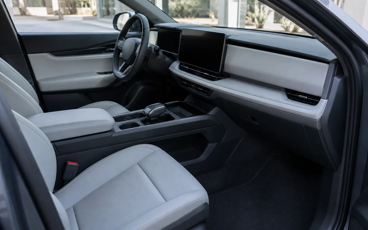 Open passenger-door view of a clean pale grey leather cabin, charcoal console, blank screens and dark footwell